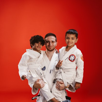 Coach holding two young athletes in a training hall