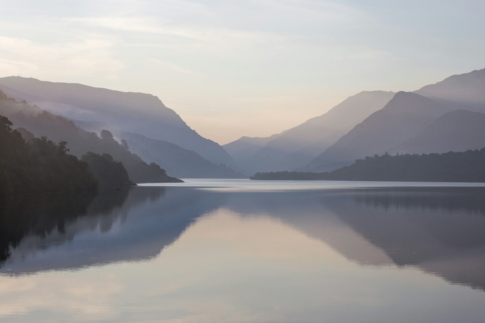 Still lake reflecting mountains at sunrise