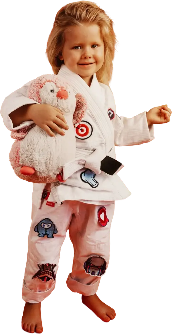 Young child in a martial arts uniform holding a plush toy