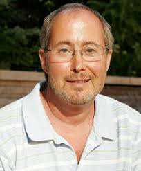 Historic black and white portrait of Anandibai Joshi, India’s first female doctor, standing in traditional attire with ornate embroidery, wearing a nose ring and jewelry, in a studio setting with a textured backdrop.