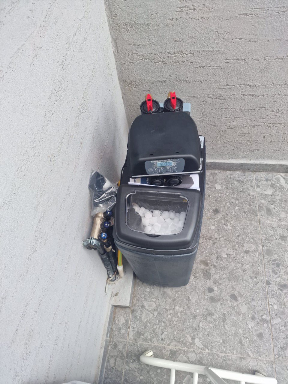 Compact water softener installed on a flat apartment roof in Cyprus next to water pipes.