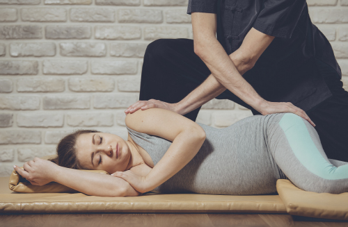 Беременная женщина проходит курс массажа у профессионального специалиста