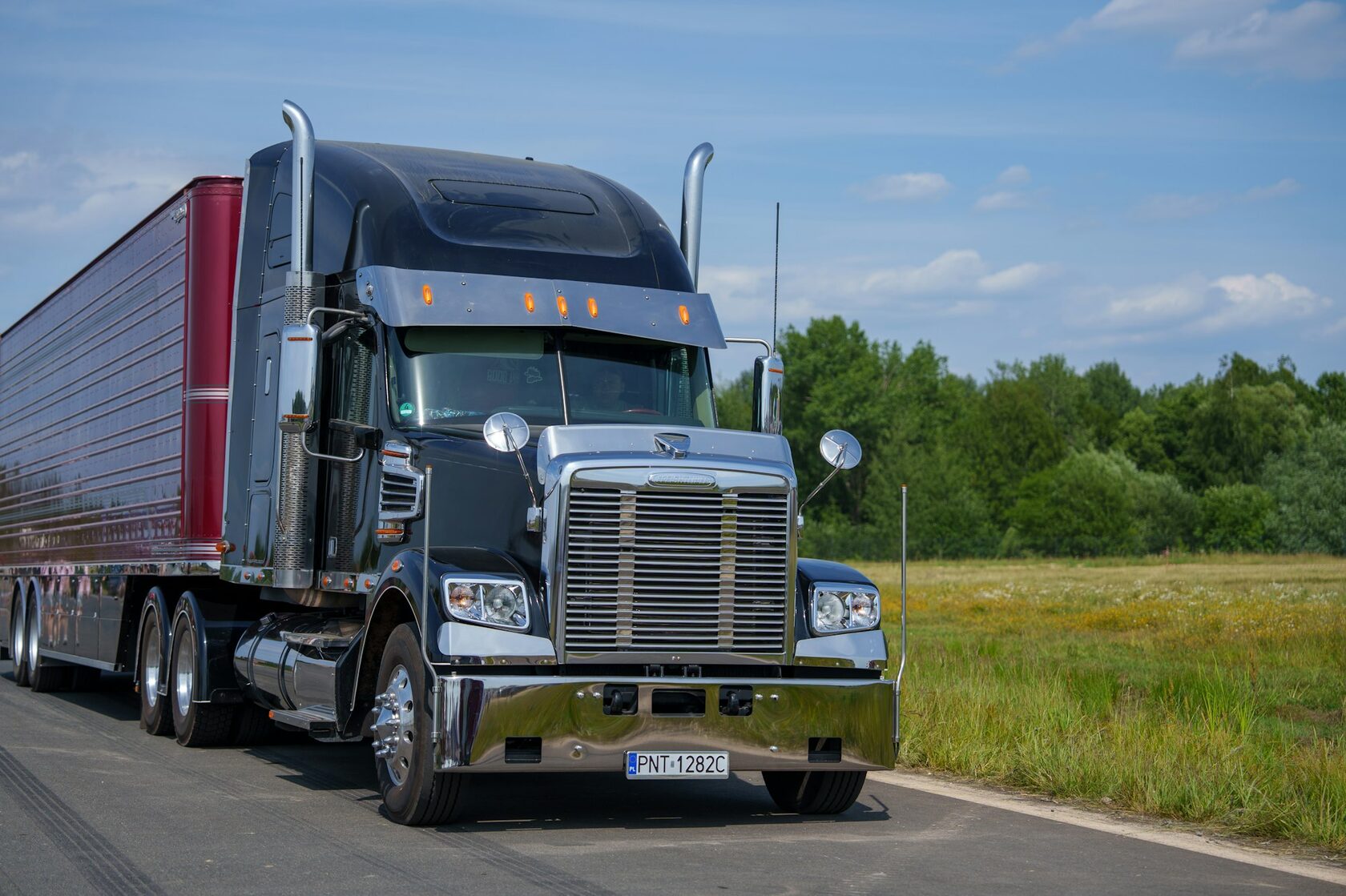 Freightliner semi truck driving open highway daytime