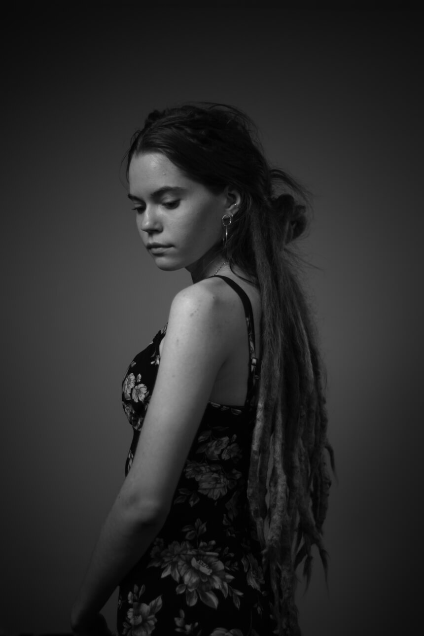 Black and white photo of a young woman in a dress looking down