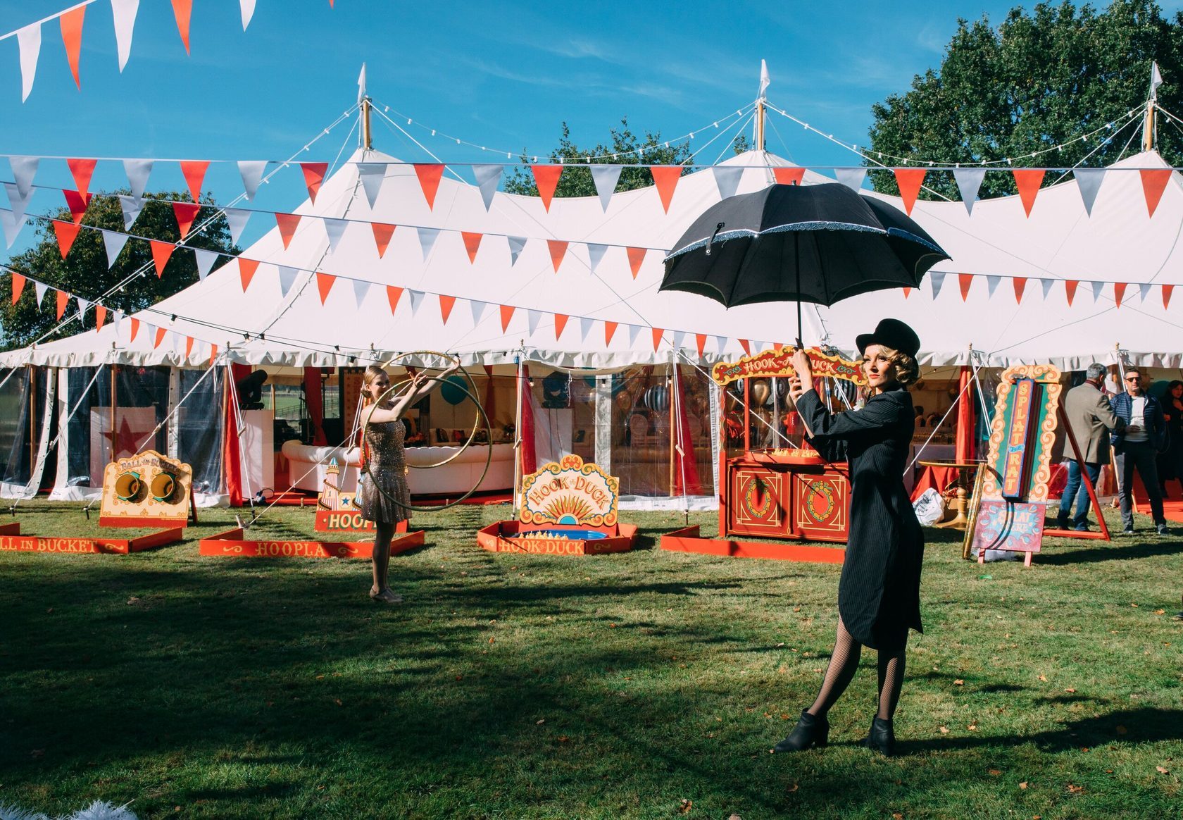 Circus artists perform on the grass in front of a white circus tent at family party