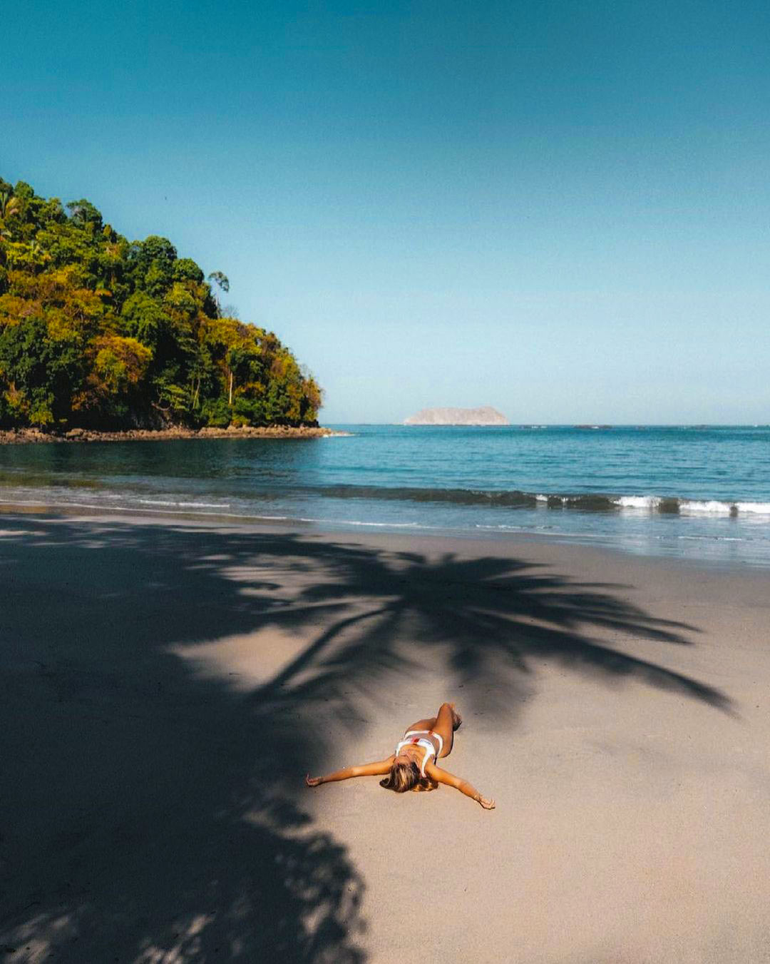 Playa Biesanz — calm, sheltered water and pale sand under a palm shadow