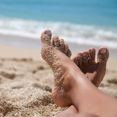 pies en la arena reposando en la playa