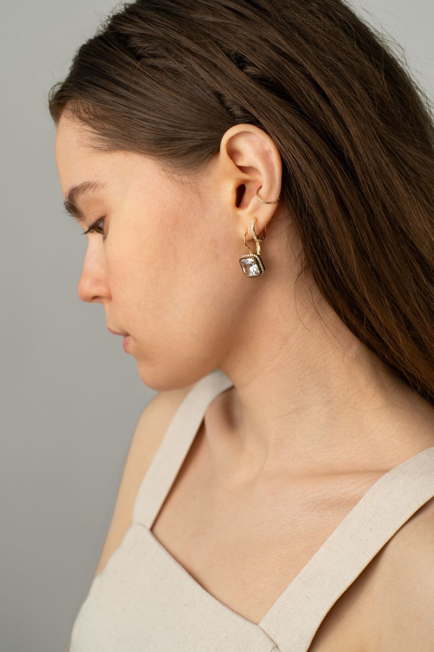 Female model posing wearing large gold earrings