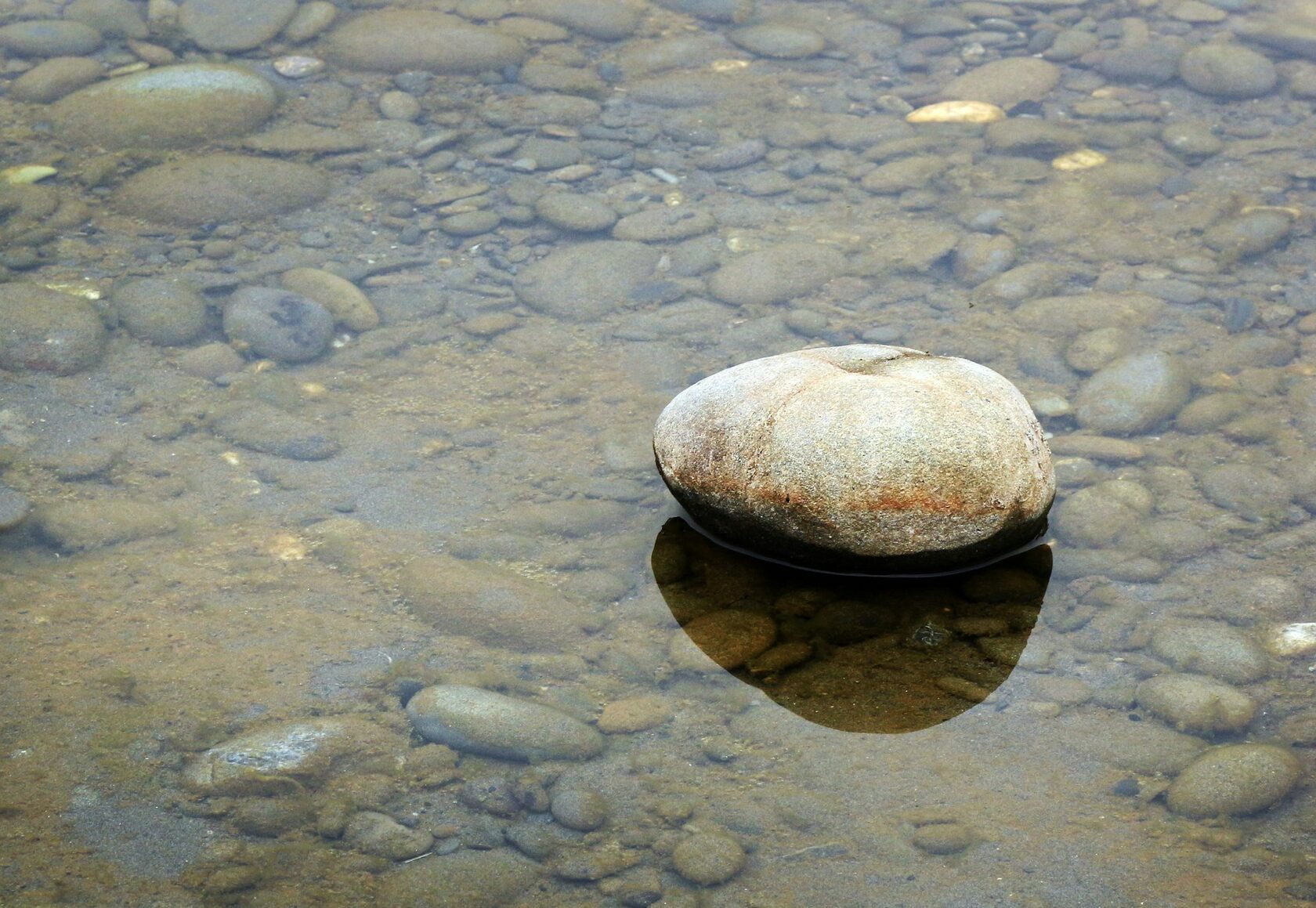 Stilles, klares Wasser über Steinen und Erde