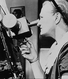 Black-and-white photo of Cecilia Payne-Gaposchkin looking through a telescope. She is shown in profile, wearing a headband and concentrating on her observations, highlighting her work as a pioneering astrophysicist.