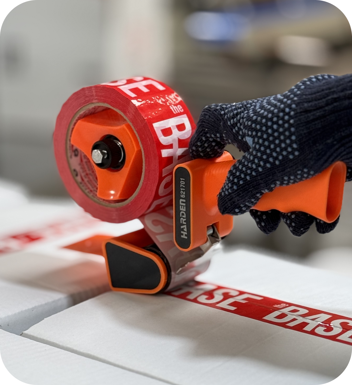 Packaging process at The Base Beverage facility with branded tape sealing a product box