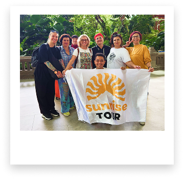 group photo of tour participants holding banner with company logo