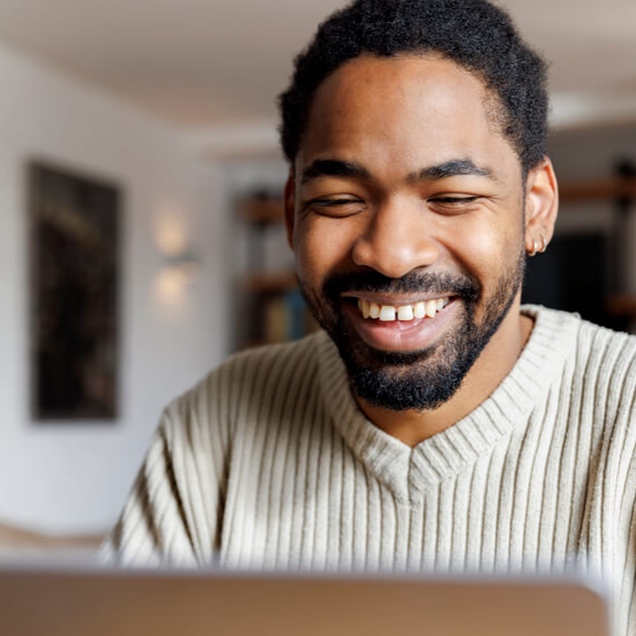 a black man smiling into the camera of an virtual meeting