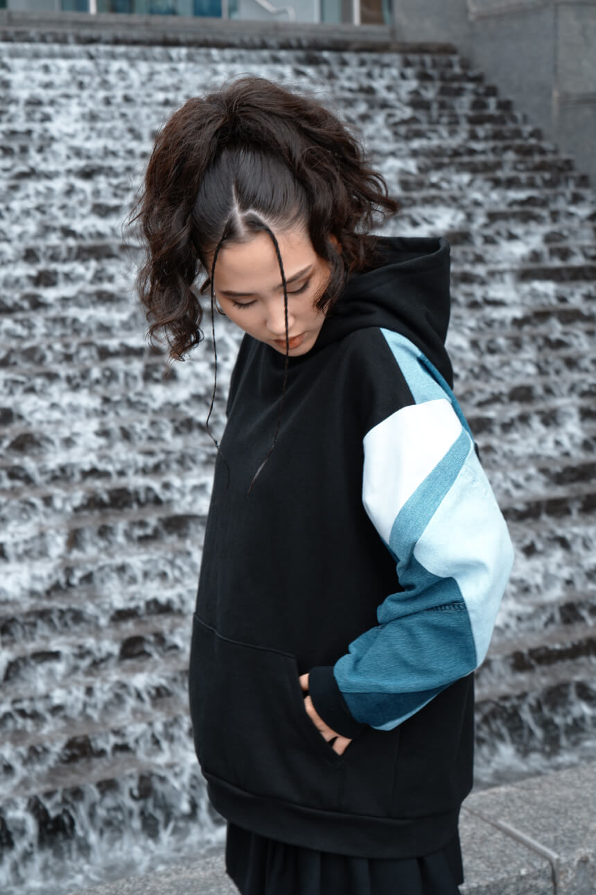 Product shot of a black and denim patchwork hoodie on a model