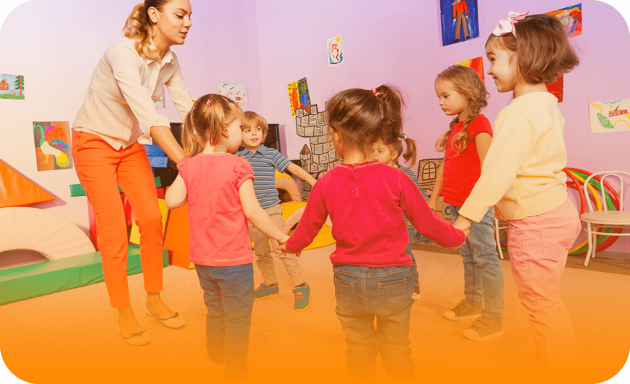 группа детей водят хоровод с воспитательницей в детском саду