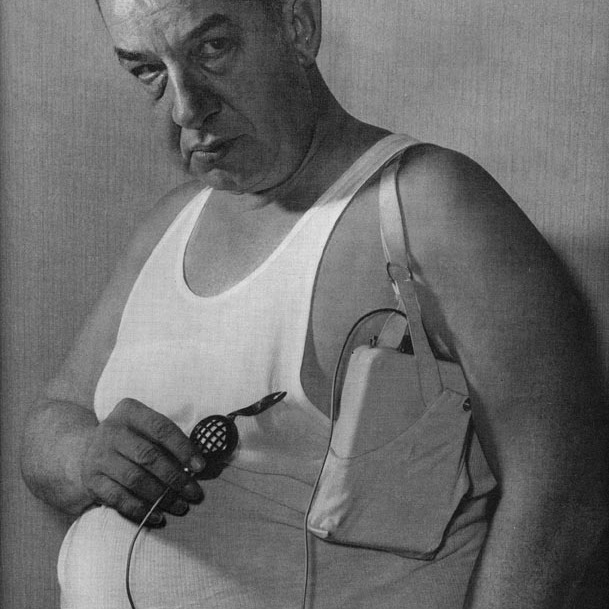 Чоловік у майці з прихованим мікрофоном під пахвою та записуючим пристроєм, ретро стиль 1970-х років, приклад шпигунського обладнання