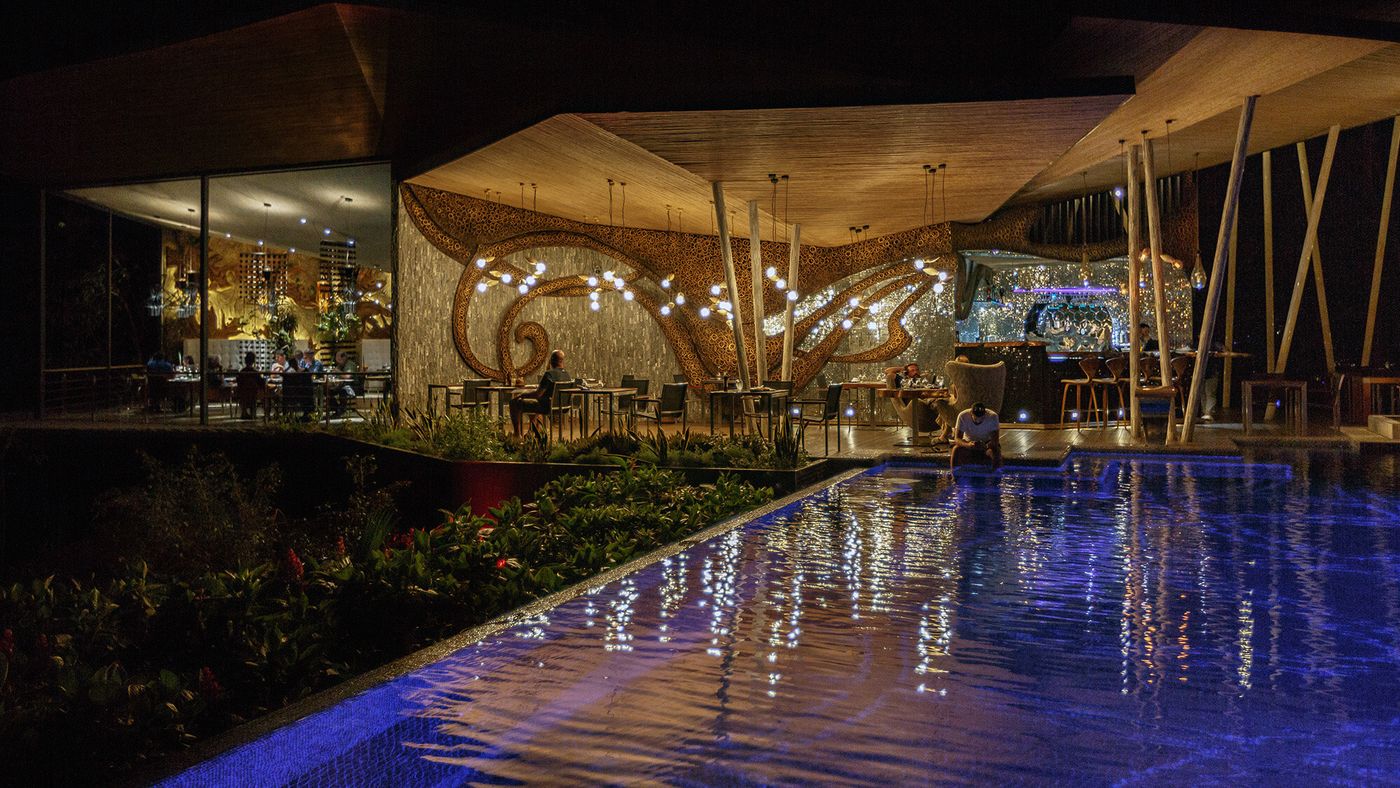 Árbol Restaurant glowing at night above the pool, Makanda by the Sea