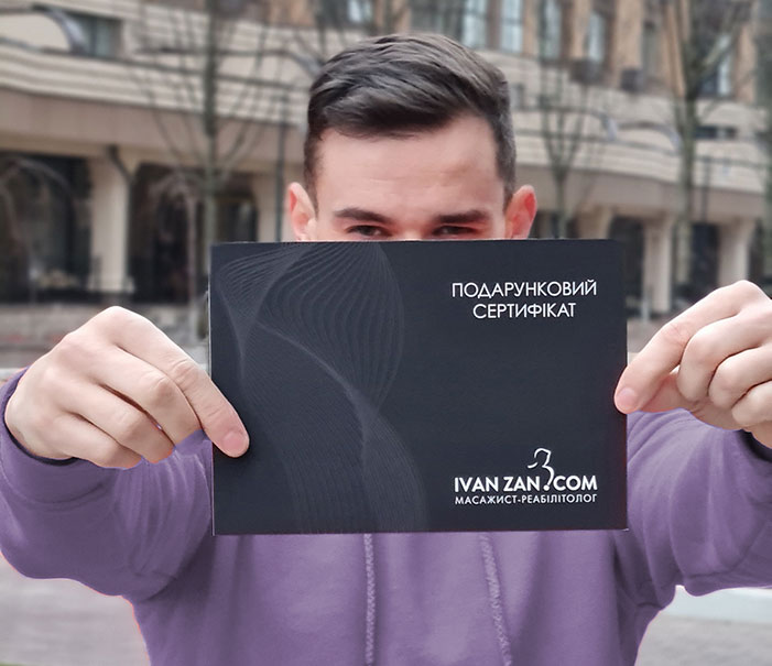хлопець тримає подарунковий сертифікат на масаж