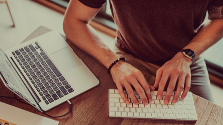 Мужские руки работают на клавиатуре за столом