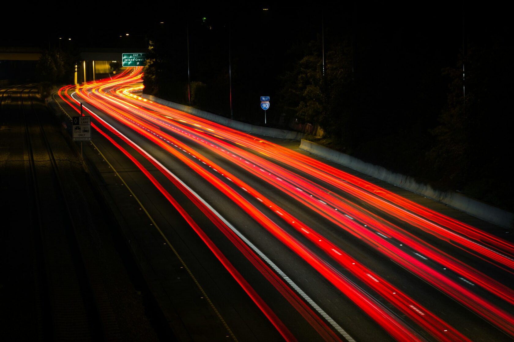 Red semi truck driving highway at night with headlights