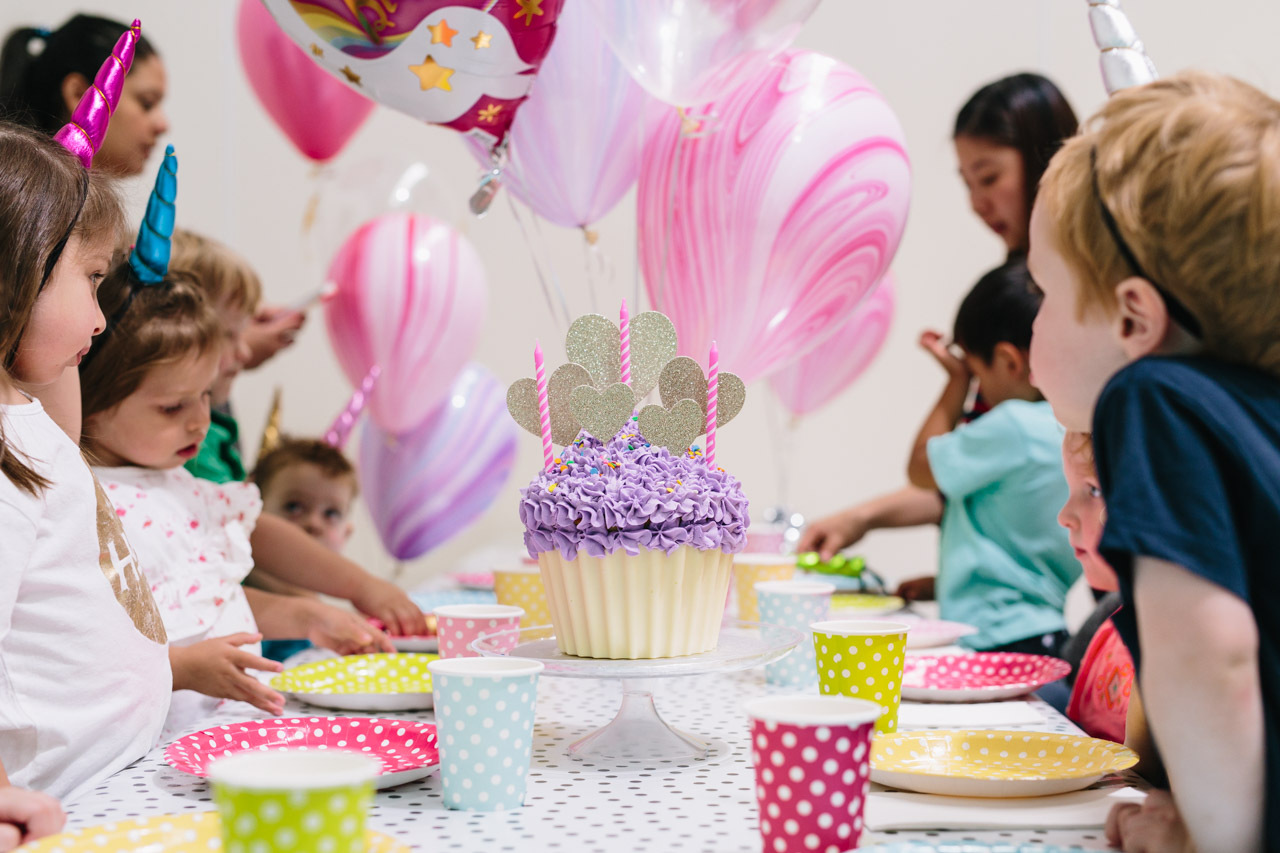 Tumbles birthday party with a giant chocolate cupcake cake and children wearing superhero masks