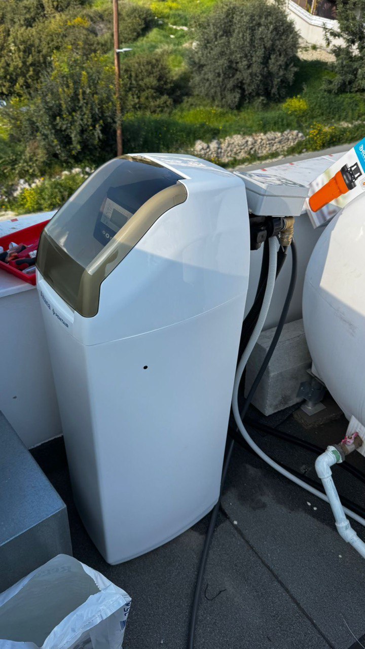 Plumber installing a water softener system and connecting it to the apartment's main water supply on the roof.