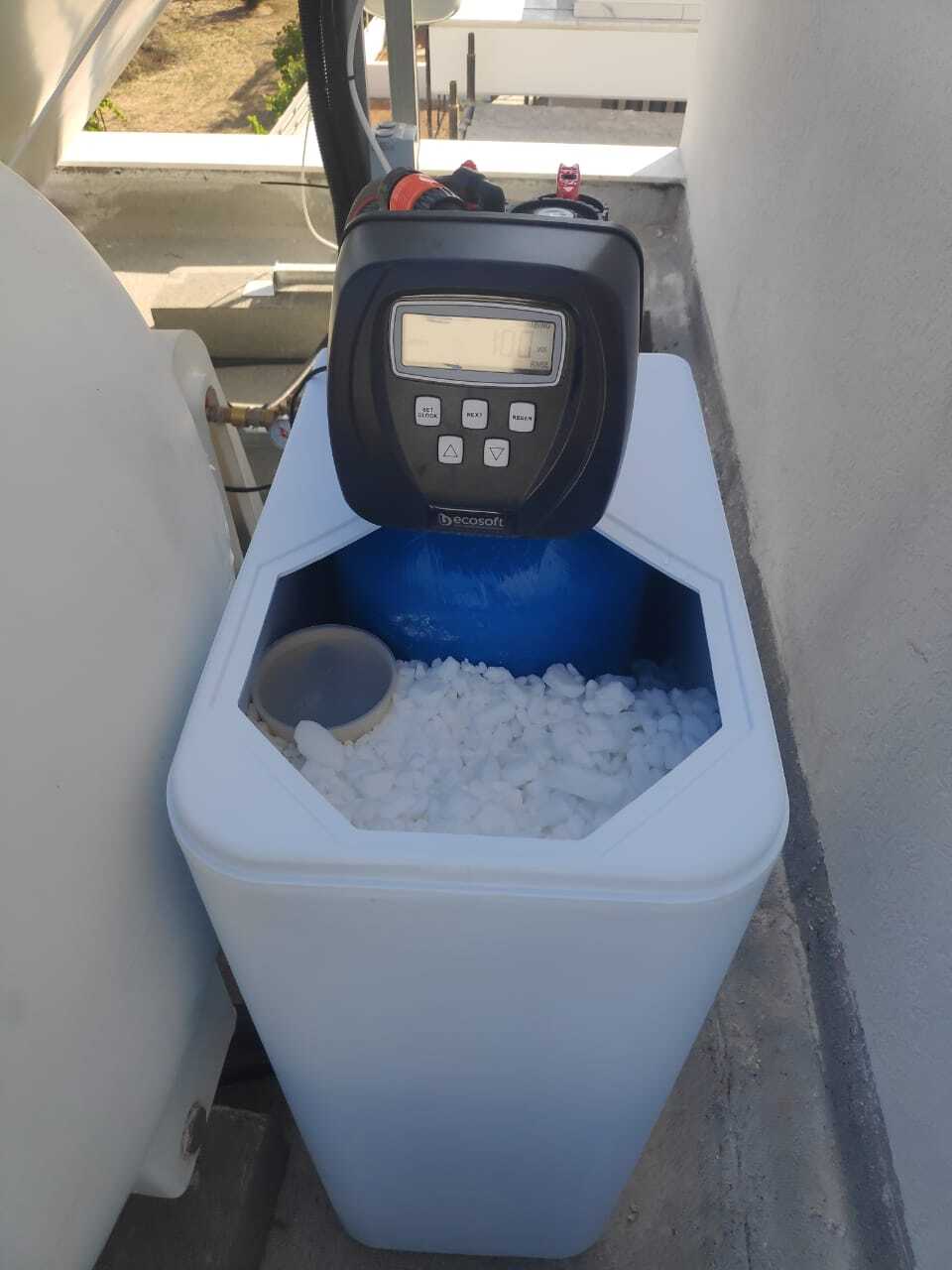 На картинке изображено реальный проект установки умягчителя воды в доме: оборудование смонтировано на крыше, подключено к системе водоснабжения с сервисными клапанами и подготовлено для защиты бойлера и бытовой техники от накипи.