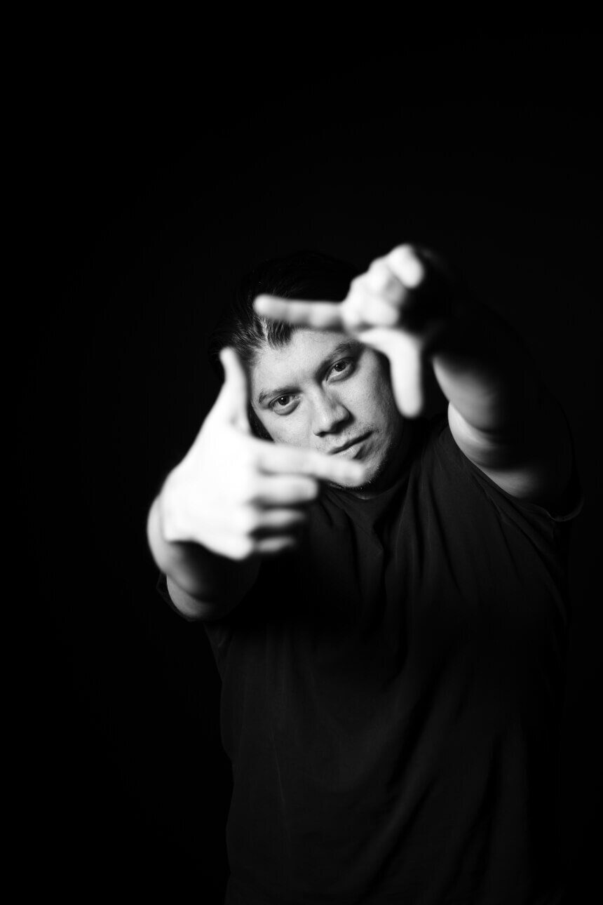 Black and white photo of a young man looking and pointing at the camera