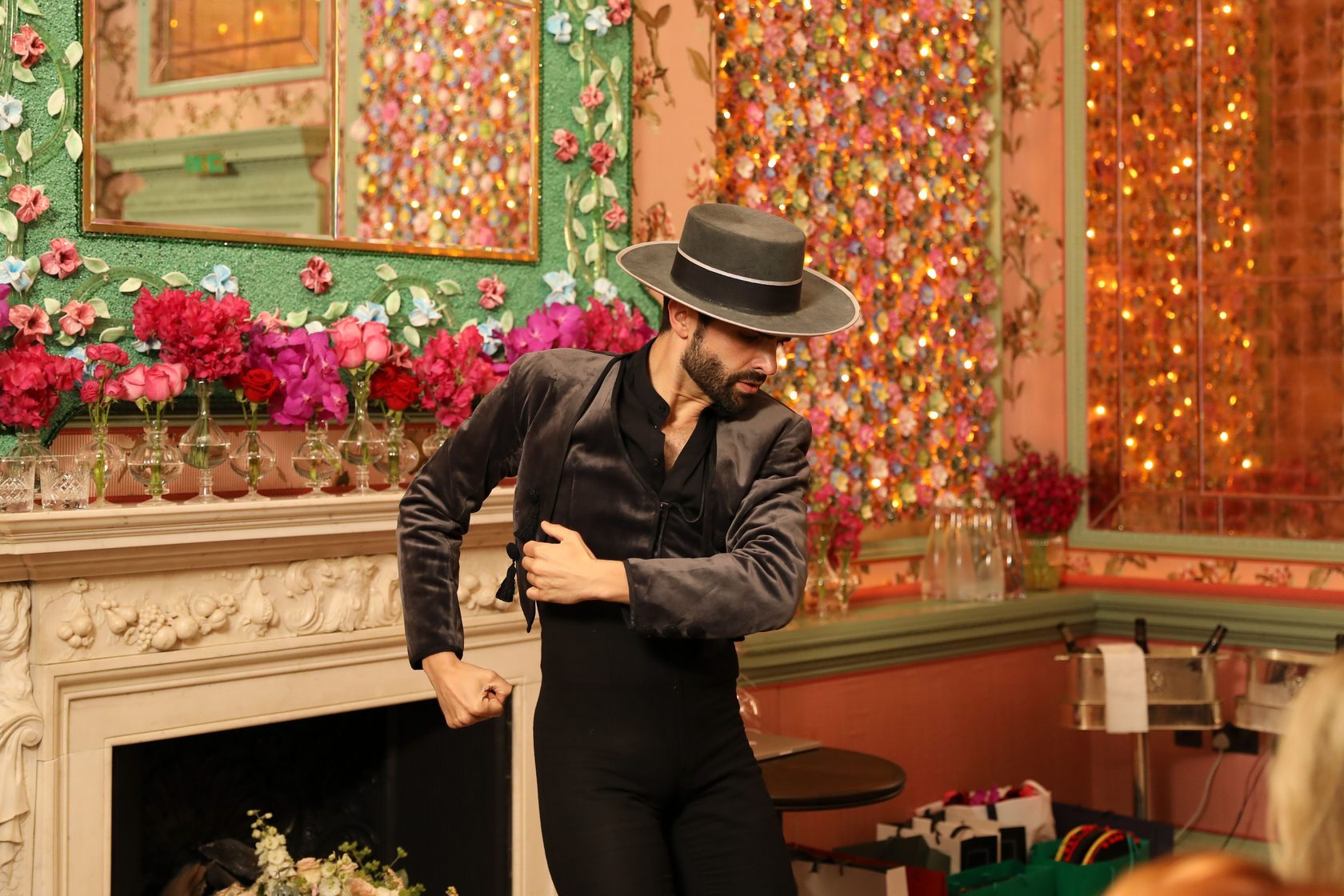Argentinian tango dancer performs in front of a mantel with flower arrangements in Annabel's members club, London